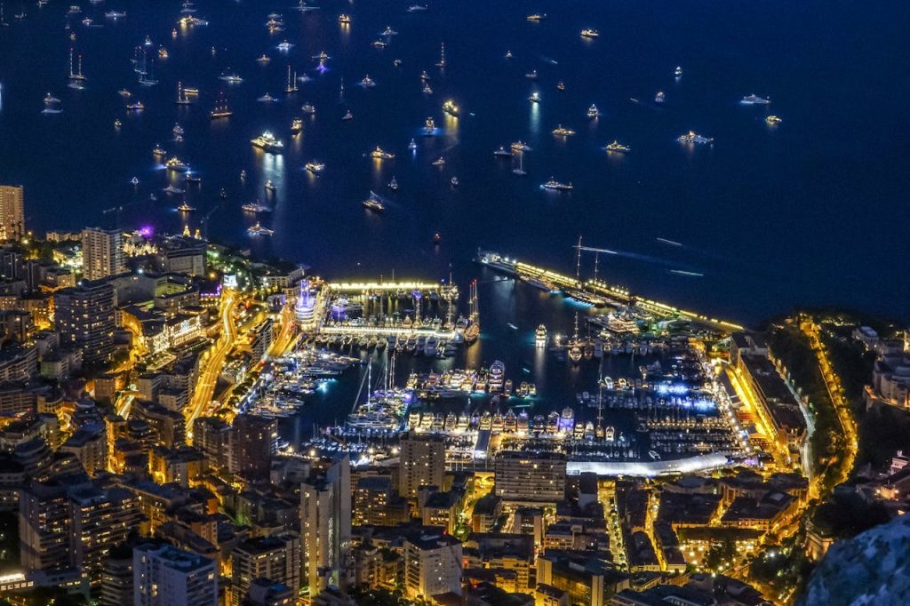 A breathtaking aerial night view of Monacos illuminated harbor with numerous yachts.