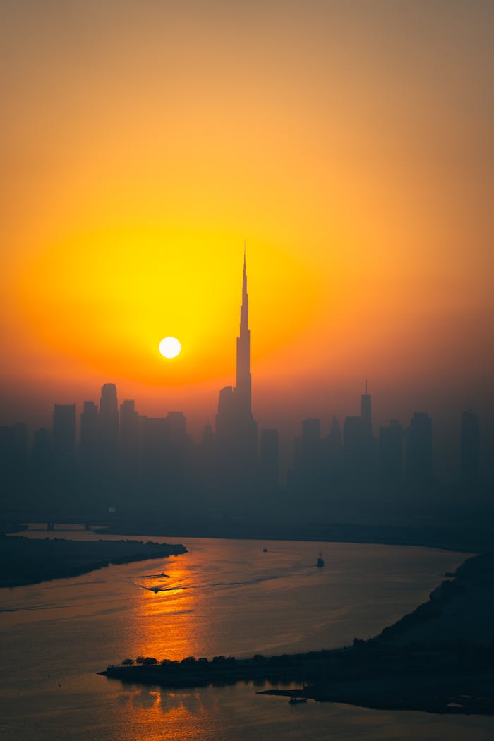 A breathtaking view of Dubai skyline with the iconic Burj Khalifa at sunset, reflecting over the water.